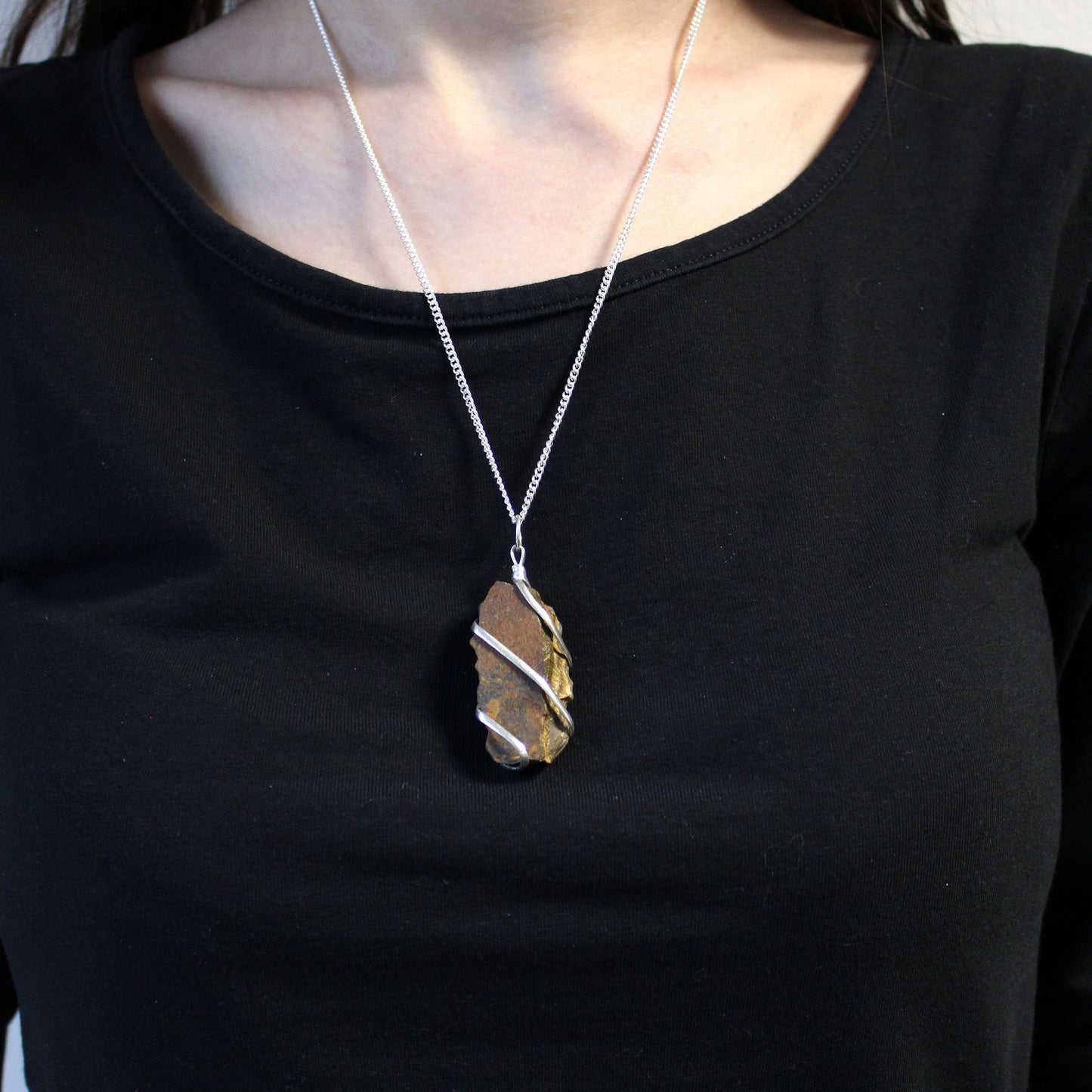 Cascade Wrapped Gemstone Necklace gedragen op zwarte kleding, ruwe Rough Tiger Eye hanger met zilverkleurige wire-wrapping, lifestyle foto