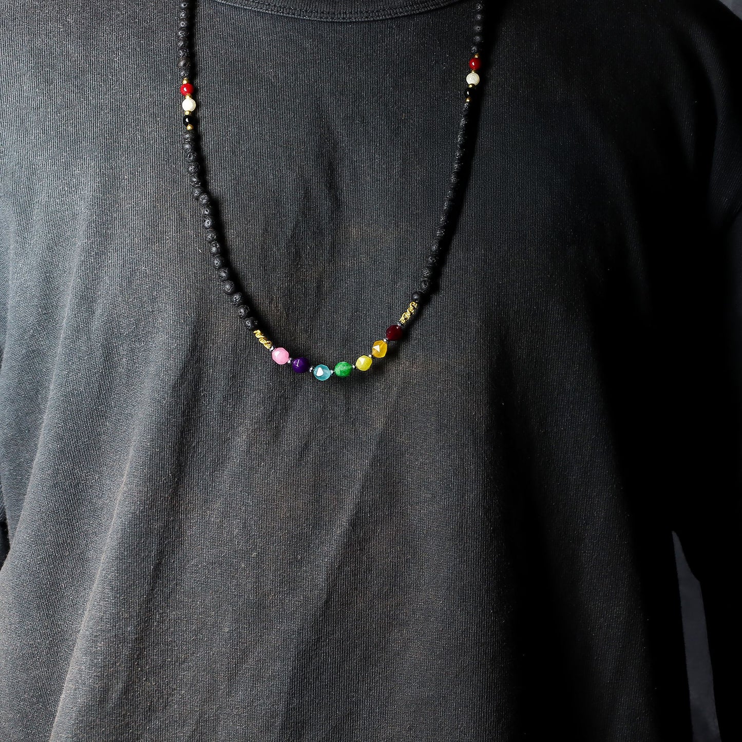 Detailweergave van een ketting van lavasteen met tri Datu-kralen in wit, rood en zwart, die bescherming en aarding symboliseren.