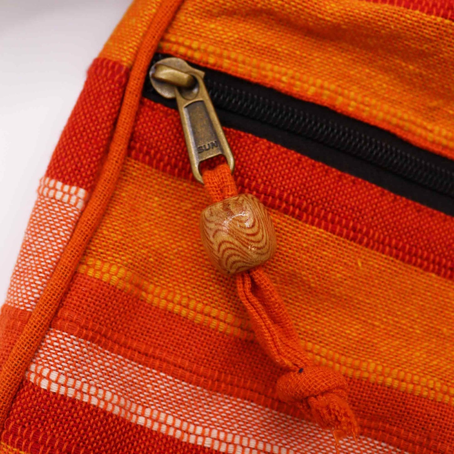 Close-up detail van een oranje gestreepte weving en traditioneel Nepalees vakmanschap op een crossbodytas