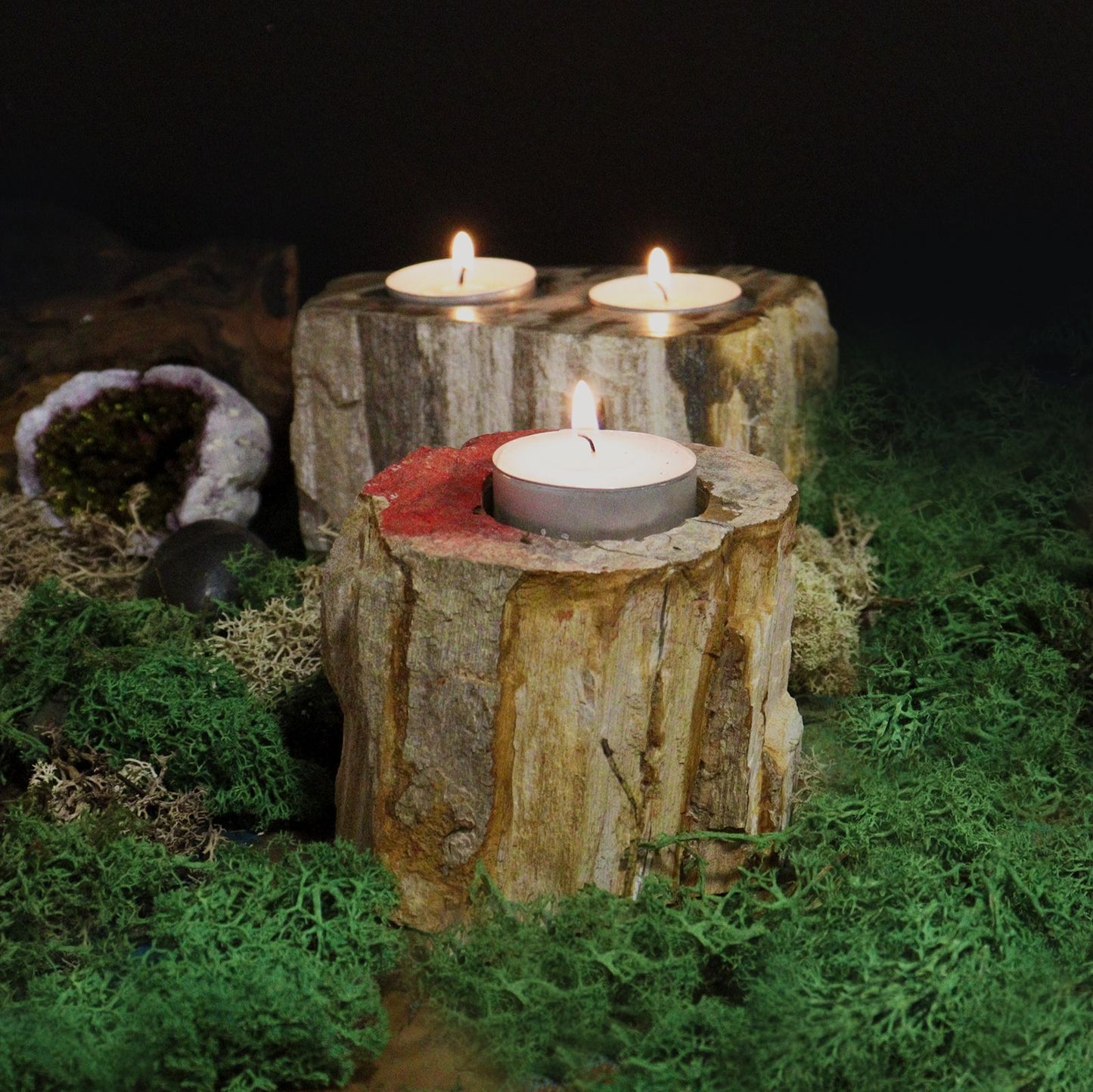 Lifestylefoto van een dubbele kandelaar van versteend hout met brandende theelichtjes, gezellige rustieke sfeer, natuurlijke woondecoratie