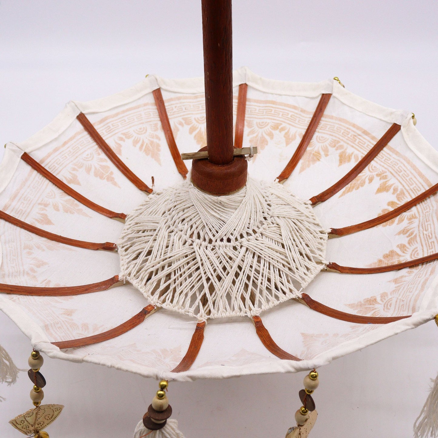 Bovenaanzicht van een Balinese parasol met gouden ornamenten op wit canvas, traditionele Indonesische decoratieve paraplu
