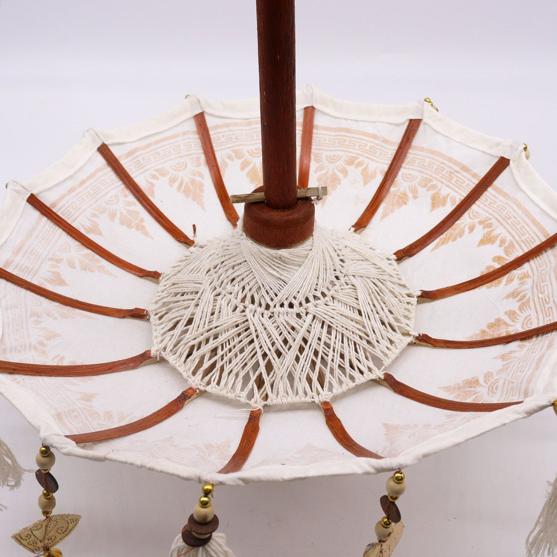 Bovenaanzicht van een Balinese parasol met gouden ornamenten op wit canvas, traditionele Indonesische decoratieve paraplu
