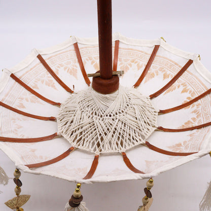 Bovenaanzicht van een Balinese parasol met gouden ornamenten op wit canvas, traditionele Indonesische decoratieve paraplu
