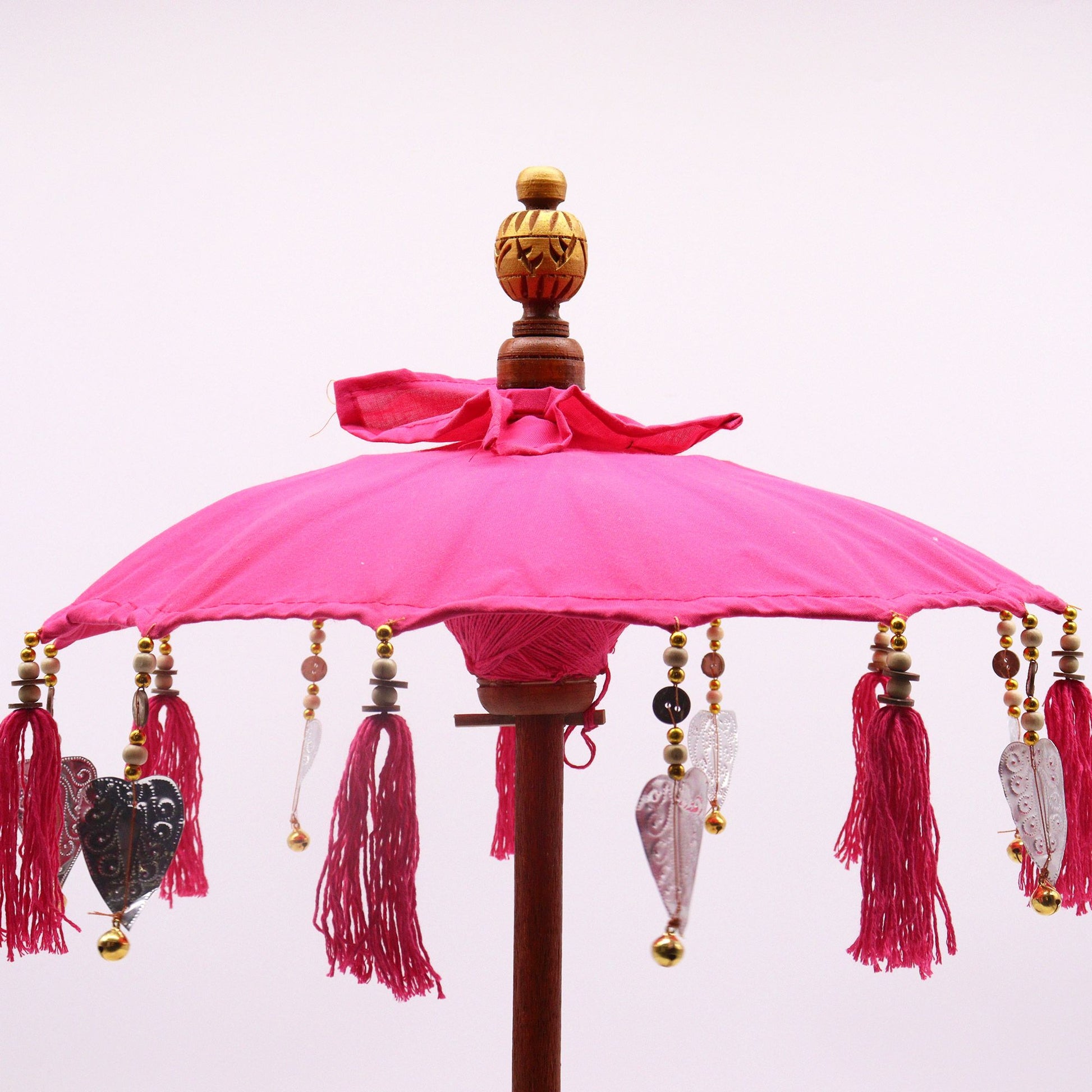 Bovenaanzicht van een Balinese parasol met levendig roze katoen en kwastjes, een traditionele Indonesische decoratieve paraplu.
