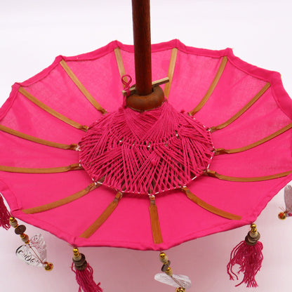 Detailopname van kleurrijke kwastjes en roze katoenen textuur op een Balinese parasol, handgemaakt vrouwelijk bohemien woonaccessoire
