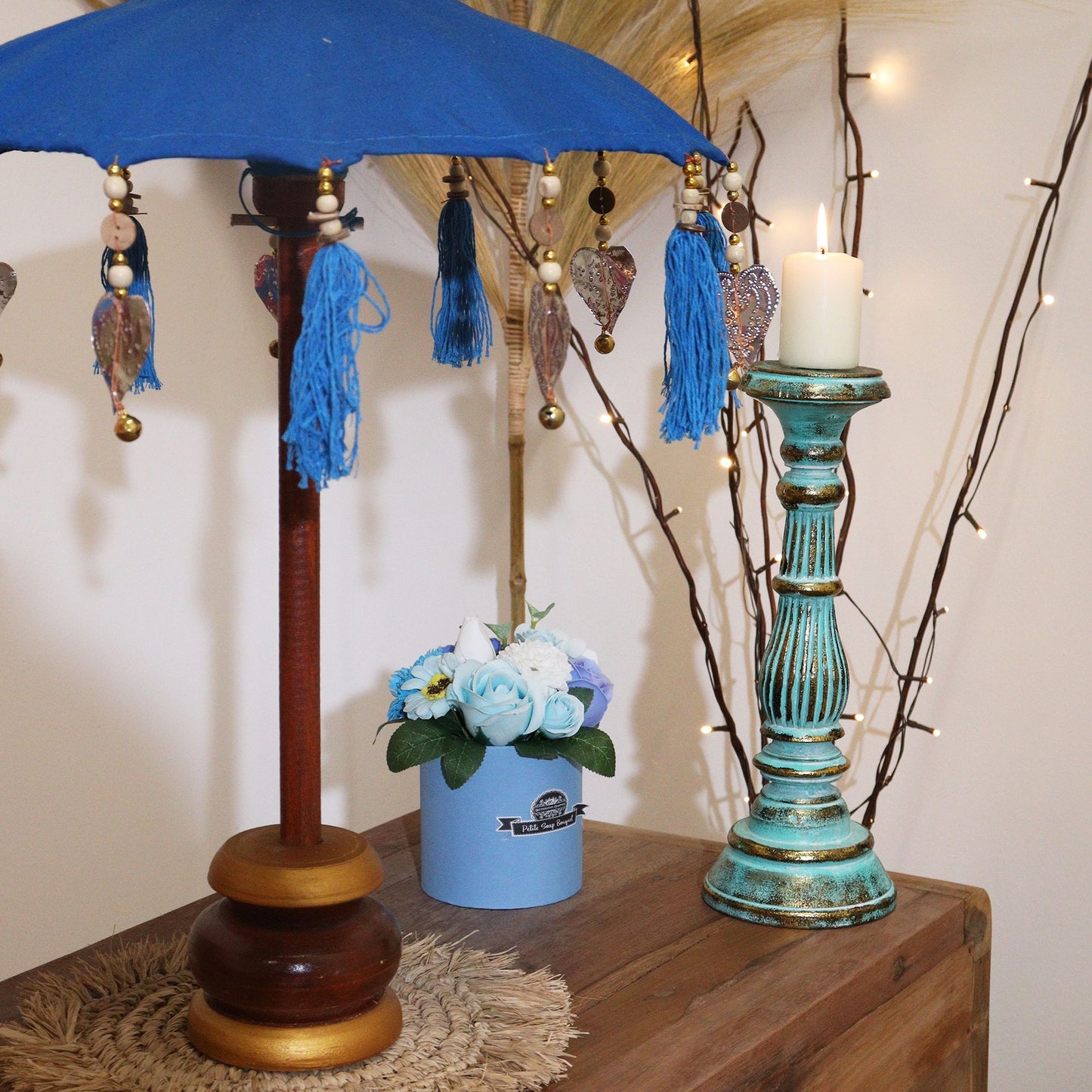 Close-up van decoratieve parasol uit Bali met turquoise katoenen stof en kleurrijke hangende kwastjes, handgemaakt Balinees vakmanschap.
