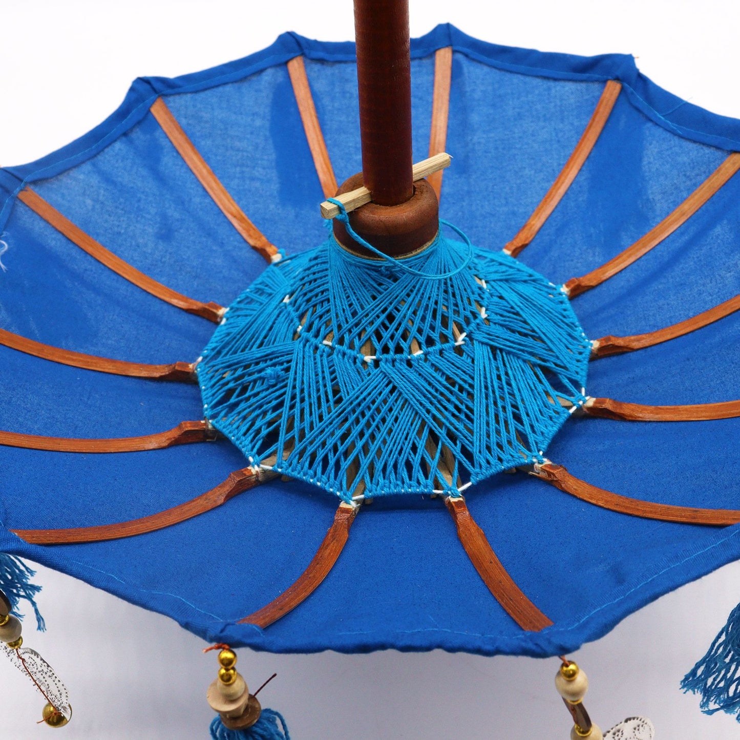 Bovenaanzicht van een Balinese parasol met levendig turquoise katoen en kwastjes, een traditionele Indonesische decoratieve paraplu.
