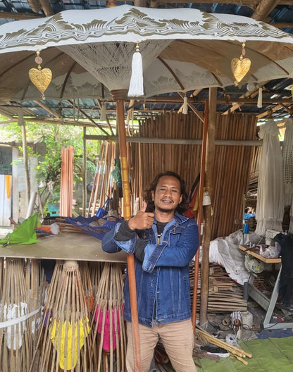 Bovenaanzicht van grote Bali-terrasparasol met natuurlijk canvas en kwastjes, traditionele Indonesische tuinparasol
