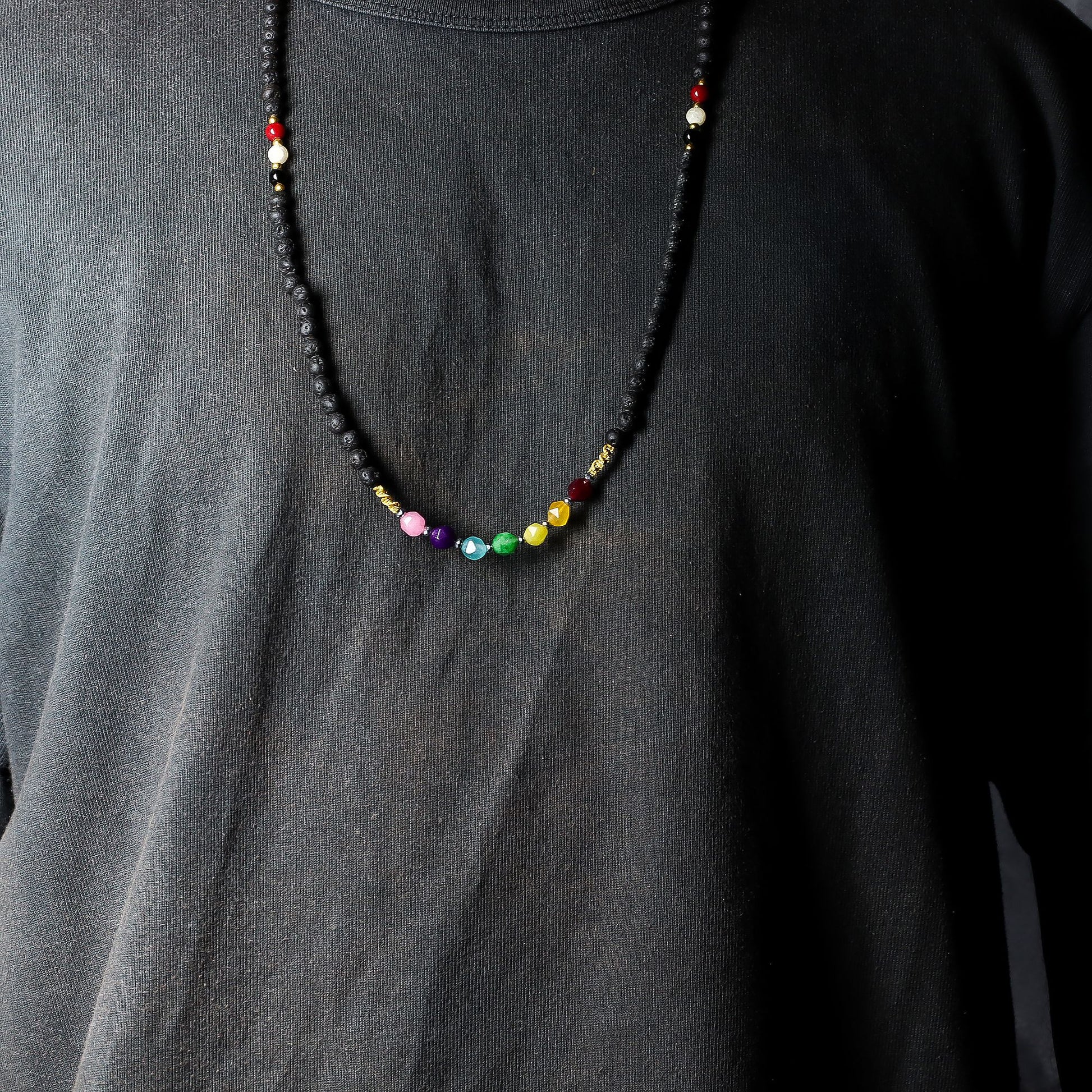 Detailweergave van een ketting van lavasteen met tri Datu-kralen in wit, rood en zwart, die bescherming en aarding symboliseren.
