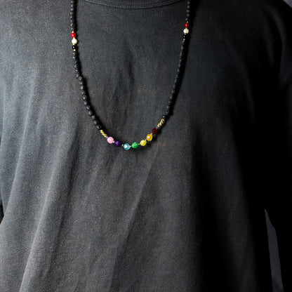 Detailweergave van een ketting van lavasteen met tri Datu-kralen in wit, rood en zwart, die bescherming en aarding symboliseren.
