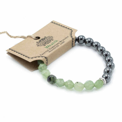 Facettenarmband van jade met magnetische sluiting en gepolijste groene edelsteen kralen op een witte achtergrond, handgemaakte sieraden voor welvaart en harmonie van het hartchakra.
