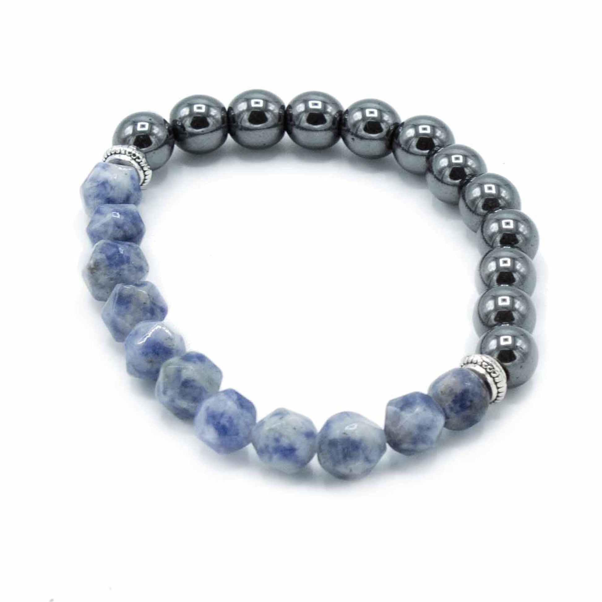 Close-up van een armband met gefacetteerde sodaliet, met geslepen en gepolijste edelstenen in diep marineblauw met witte calcietpatronen en sprankelende lichtreflecties, met magnetische metalen sluiting.
