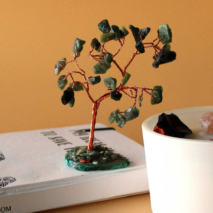 Close-up van groene aventurijn edelsteen wensboom op natuurlijke groene agaat basis met draadgewikkelde stenen, handgemaakt decoratiestuk voor overvloed