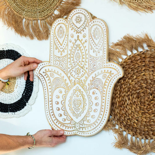 Close-up van gedetailleerde, met de hand gesneden details op een Hamsa-wandplaat met witgekalkte afwerking
