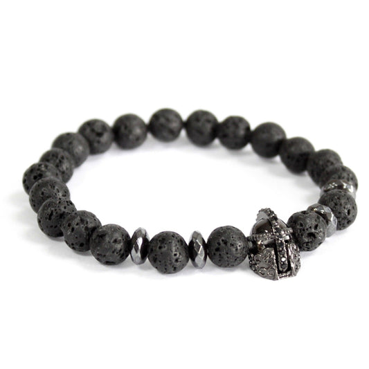 Lava stone ridderhelm armband met natuurlijke zwarte vulkanische kralen en zilveren ridderhelm bedeltje op witte achtergrond, elastische bohemian sieraden voor moed en bescherming van het wortelchakra.
