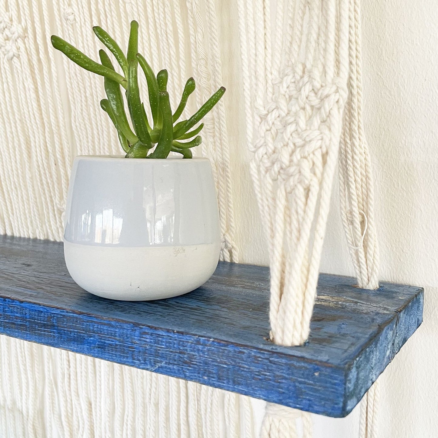 Bohemian macramé hangende plank met blauwe accenten voor het uitstallen van woonaccessoires
