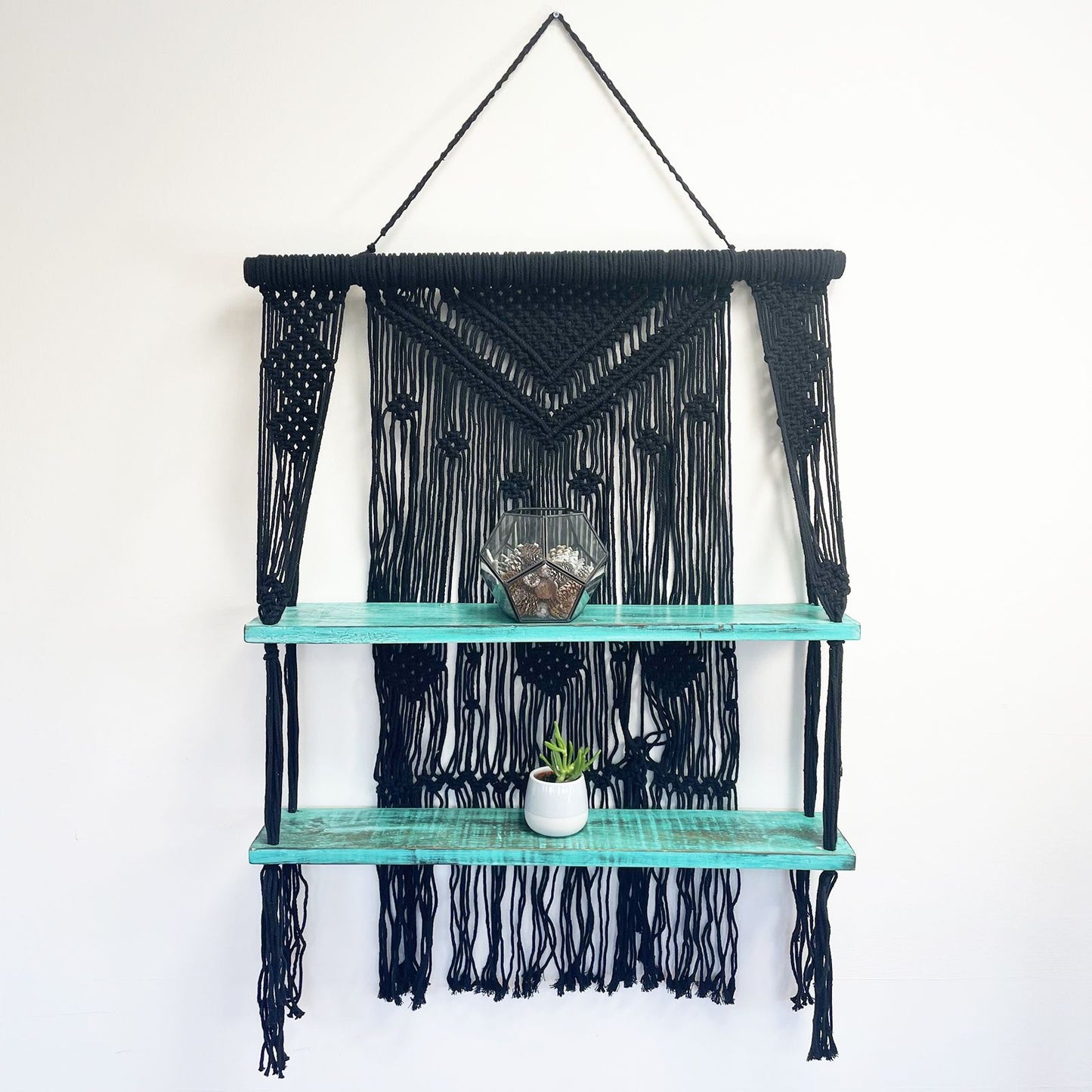 Macramé hangplank gestyled met planten en decoraties, turquoise zwart bohemien interieur


