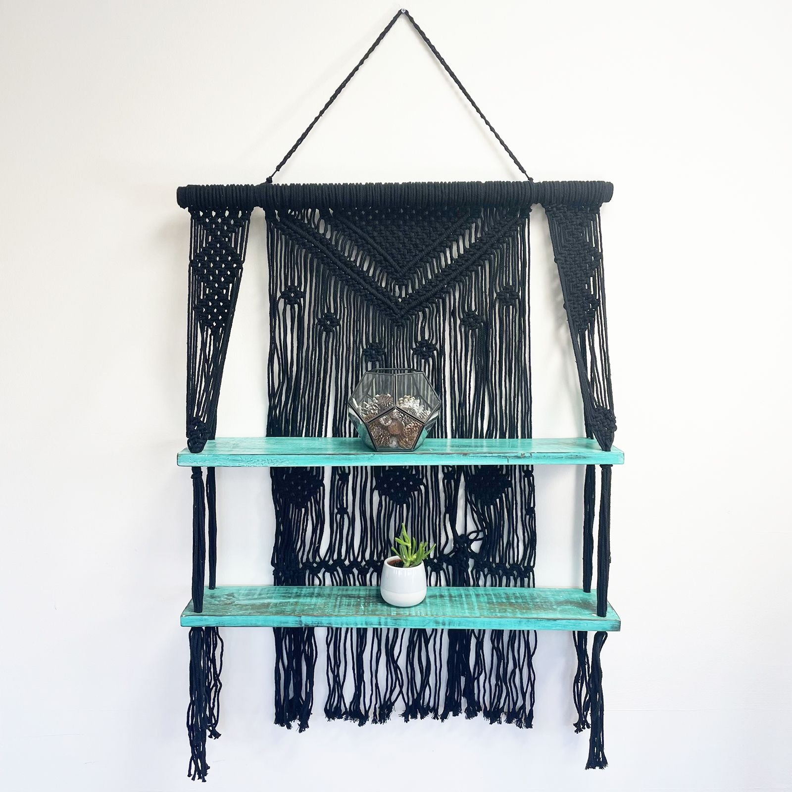 Macramé hangplank gestyled met planten en decoraties, turquoise zwart bohemien interieur


