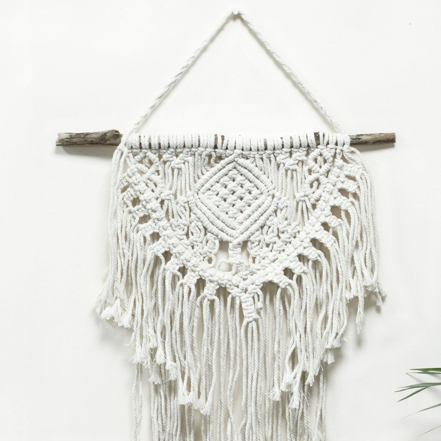 Natuurlijke katoenen macramé wanddecoratie met tribaal geïnspireerd hartmotief voor boho-interieurs
