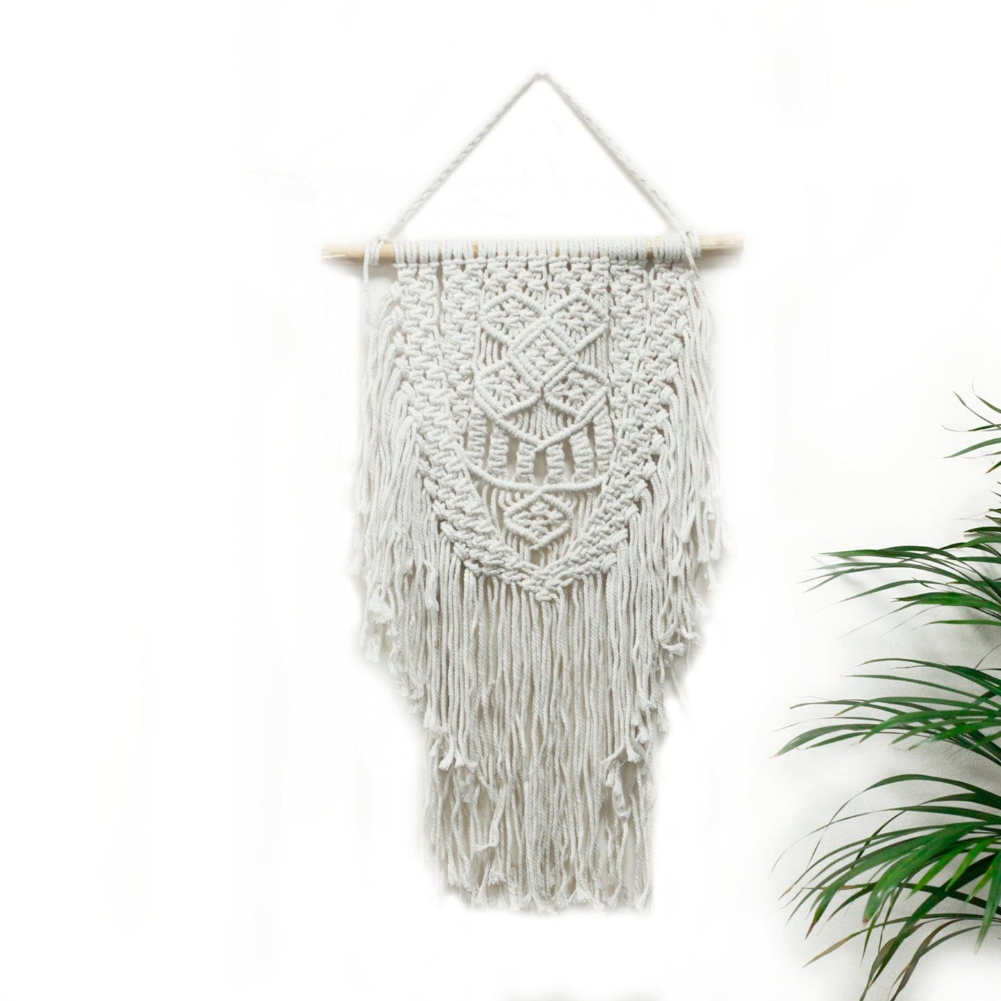 Overvloedige macramé wanddecoratie in bohemien interieur met planten en natuurlijke decoraties

