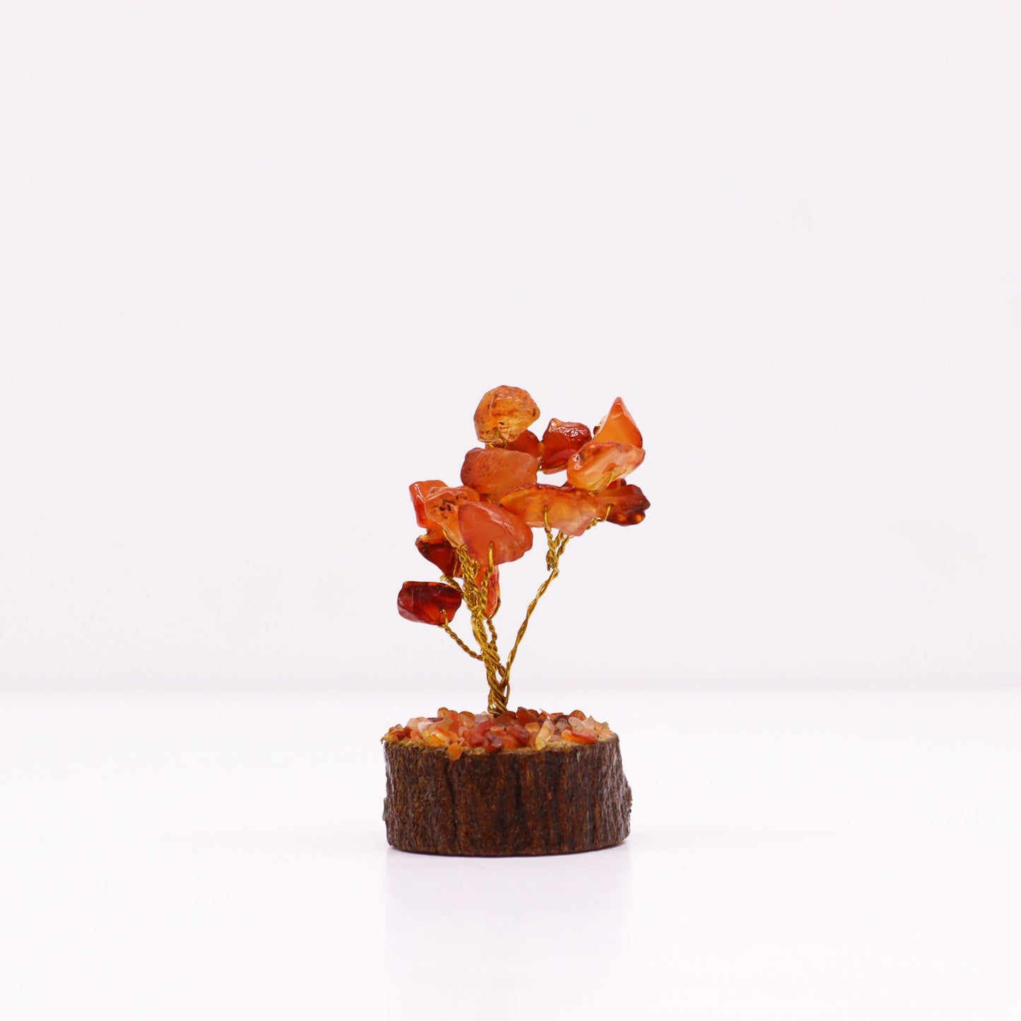 Detailfoto van mini-karneool edelsteenboom met oranje kristallen stukjes en natuurlijke houten voet, handgemaakt creatief kunstwerkje in zakformaat.

