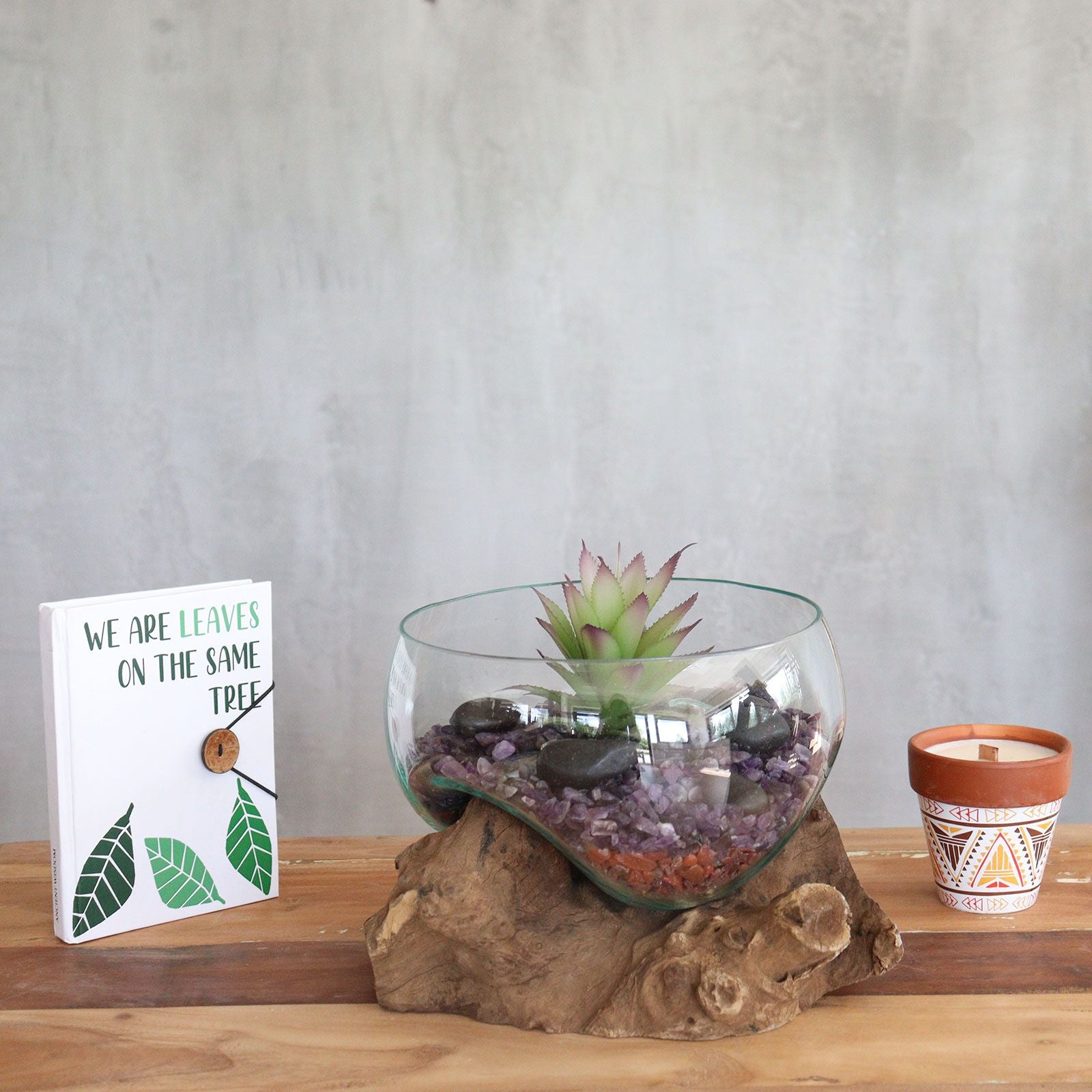 Grote open kom van gesmolten glas, gebruikt als drijvende kandelaar met een voet van natuurlijk hout, sfeervol decoratiestuk uit Bali
