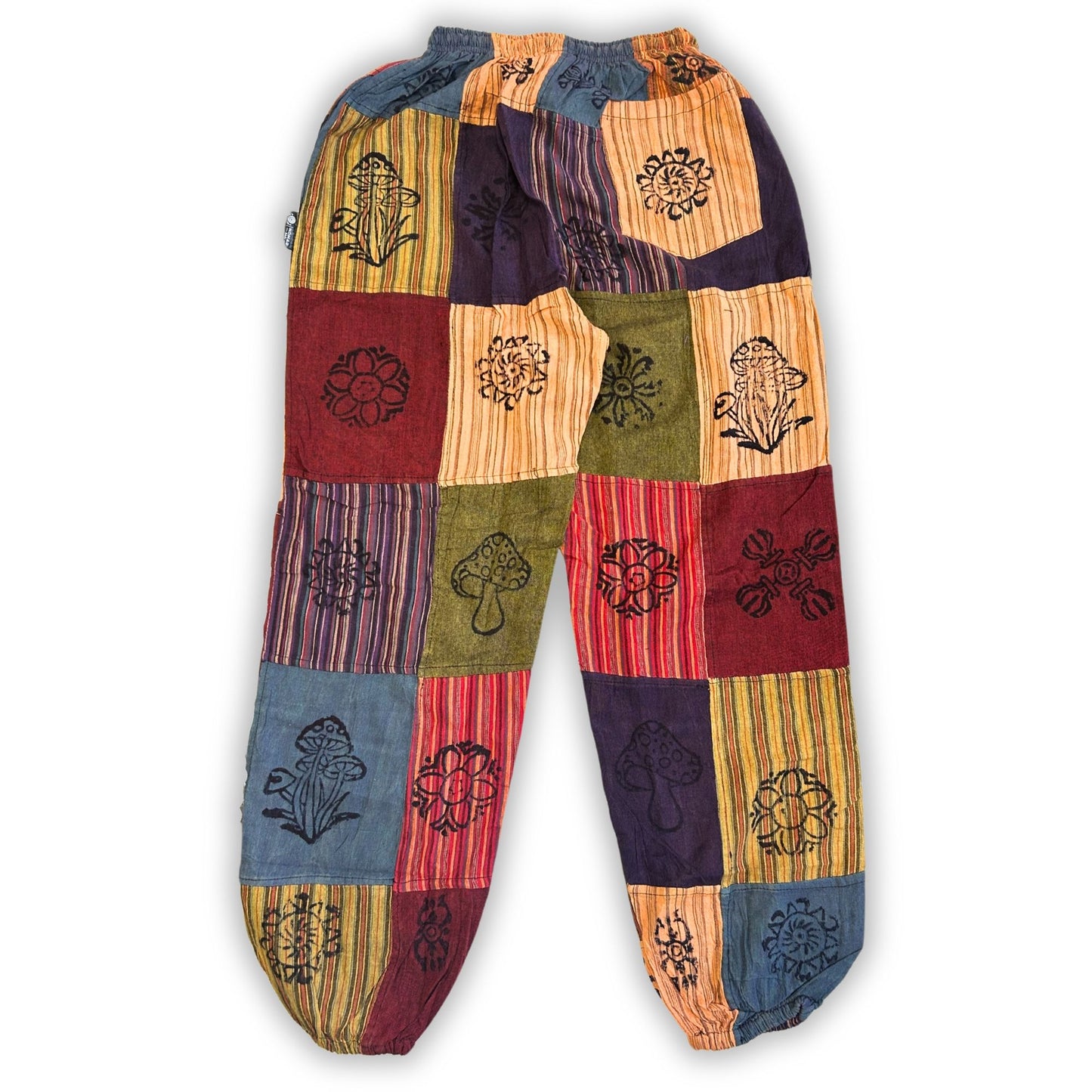 Close-up detail van paddestoelenblokprintpatroon op zachte, soepel vallende bohemian broek in aardse oranje- en bruintinten
