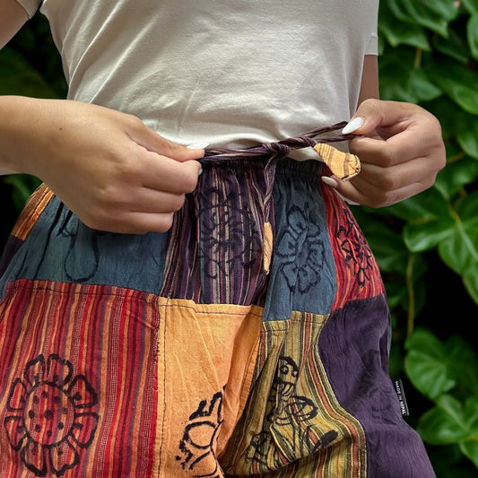 Detail van elastische tailleband en levendige oranje paddestoelmotieven op nomadische sari-broek
