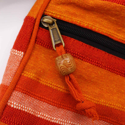Close-up detail van een oranje gestreepte weving en traditioneel Nepalees vakmanschap op een crossbodytas

