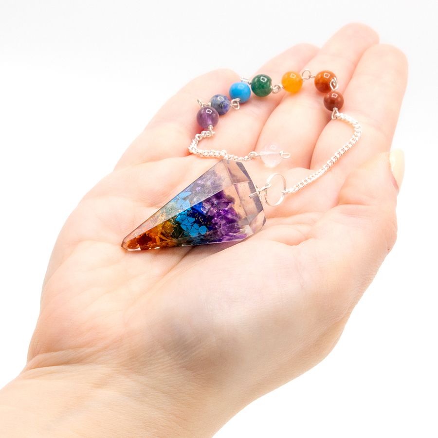 Orgoniet chakra pendel met alle zeven chakra stenen in de hand, energie healing en balancerend hulpmiddel
