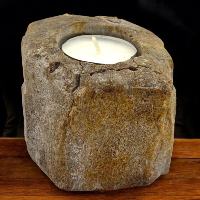 Zijaanzicht van een enkele kandelaar van versteend hout met unieke kleuren en natuurlijke scheuren, een antiek fossiel houtaccent voor in huis.