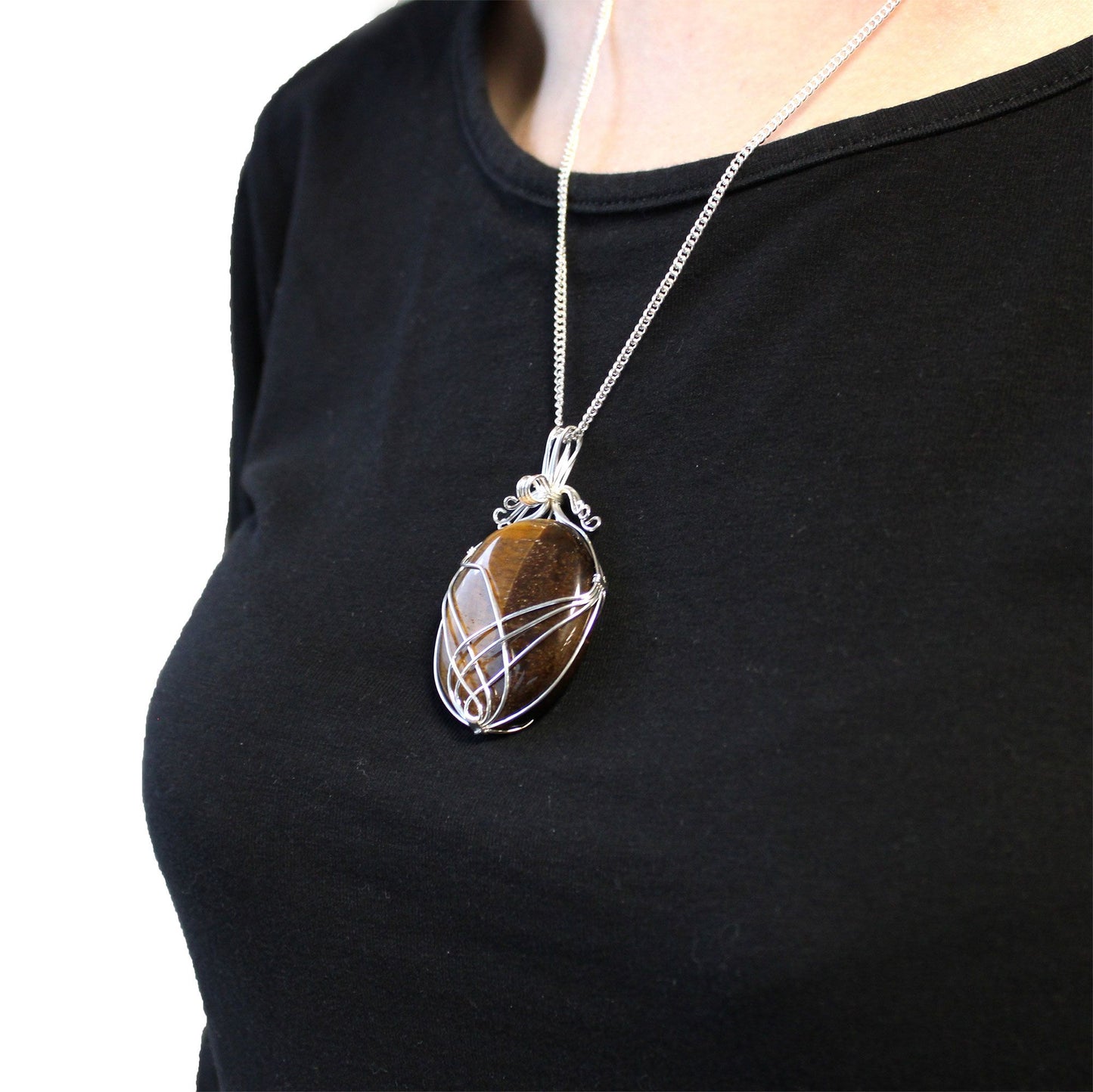 Lifestylefoto van een ketting met een hangertje van tijgeroog in swirl-wikkeling, die laat zien dat dit een veelzijdig accessoire is met een krachtige uitstraling voor elke gelegenheid.
