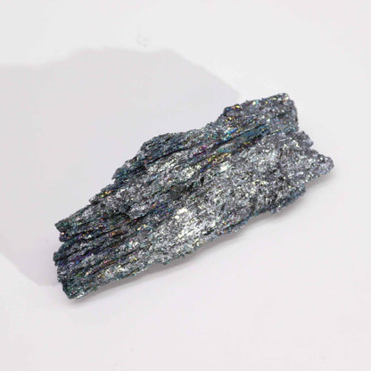 Regenboogkleurige titanium chakra-steen op een hand, met een iriserend kleurenspectrum
