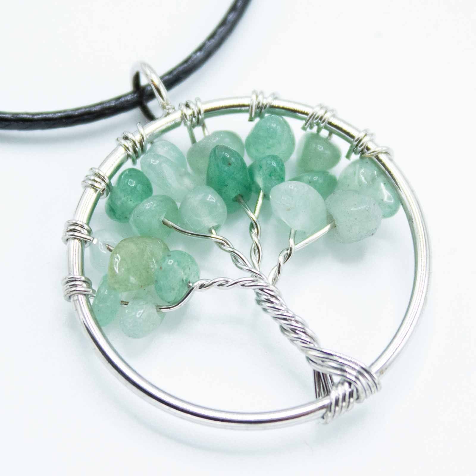 Close-up van jade Tree of Life-hanger met groene edelsteenachtergrond en metalen boomsymbool voor healing van het hartchakra

