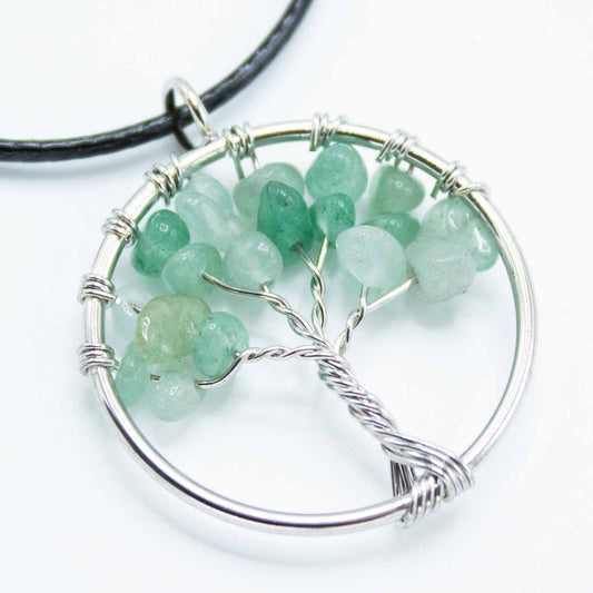Close-up van jade Tree of Life-hanger met groene edelsteenachtergrond en metalen boomsymbool voor healing van het hartchakra

