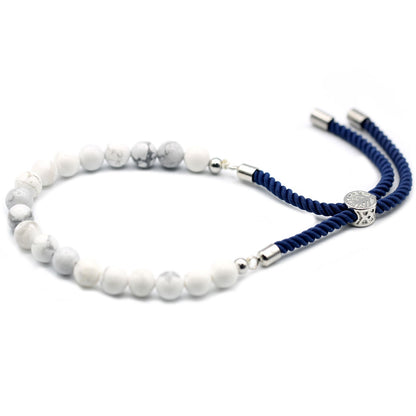 Witte howliet verzilverde marineblauwe kettingarmband met natuurlijke witte edelsteen kralen en marineblauw verstelbaar koord met 925 zilveren schuifgesp op witte achtergrond
