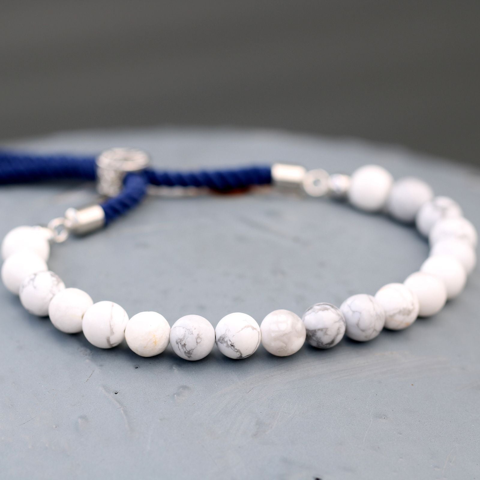 Witte howliet verzilverde marineblauwe kettingarmband met verstelbaar marineblauw koord met zilveren sluiting en natuurlijke witte howliet edelstenen.
