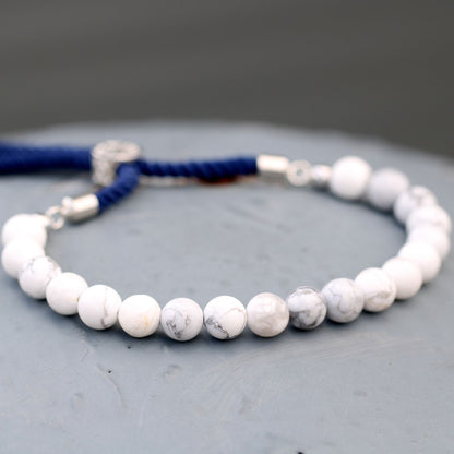 Witte howliet verzilverde marineblauwe kettingarmband met verstelbaar marineblauw koord met zilveren sluiting en natuurlijke witte howliet edelstenen.
