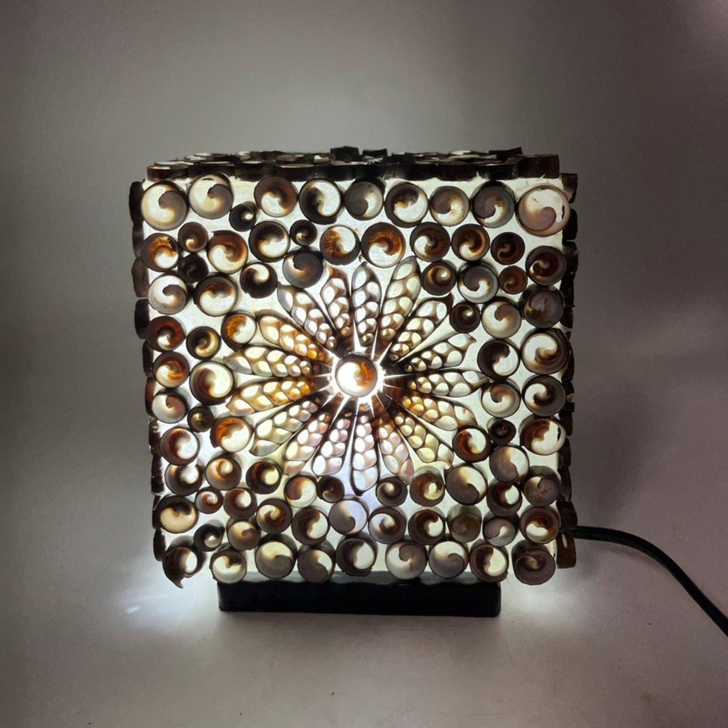Close-up van chocolate twist schelpen lamp met natuurlijke schelpen en warm licht, handgemaakt
