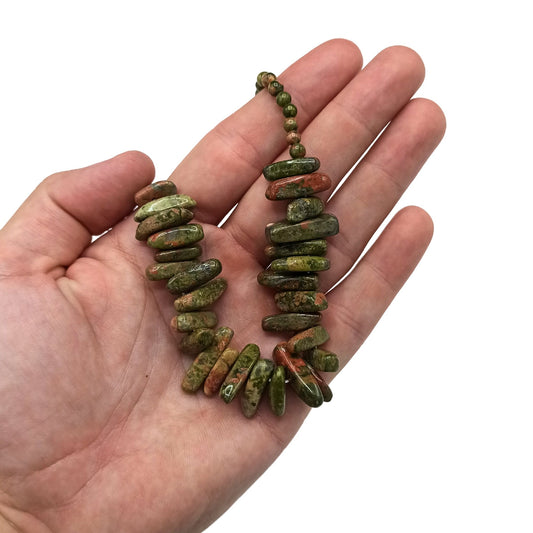 Close-up mos agaat edelsteenchips in elegante ketting met karakteristieke groene mospatronen
