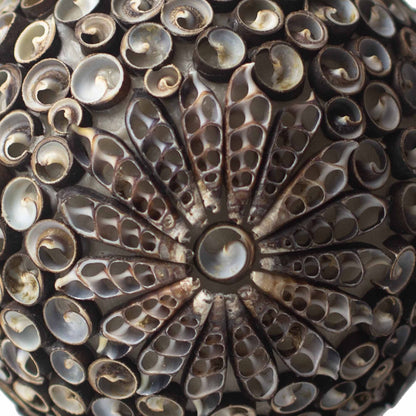 Detail van handgemaakte schelpen lamp met ovaal patroon en rustieke gloed
