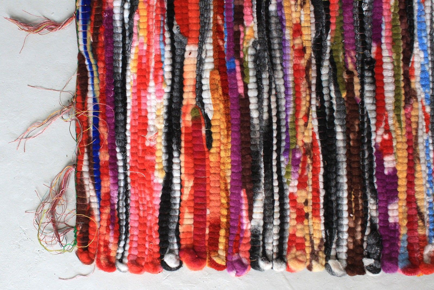 Close-up detail van gerecycled tapijt kleed met kleurrijke stroken in oranje, blauw, groen en rood, traditionele Indiase weeftechniek
