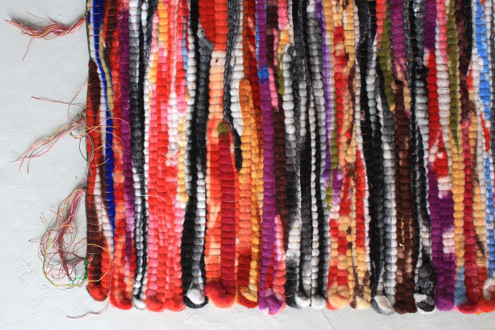 Close-up detail van gerecycled tapijt kleed met kleurrijke stroken in oranje, blauw, groen en rood, traditionele Indiase weeftechniek
